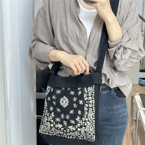 Detail of black canvas shoulder bag with white paisley bandana print and wide strap