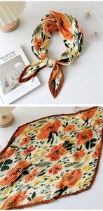 Detail of floral pleated satin scarf with accordion texture and orange botanical patterns