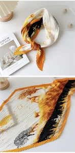 Detail of pleated silk-feel scarf featuring orange and black ink art patterns and texture