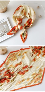 Detailed view of accordion pleated square scarf featuring orange floral prints on white silk