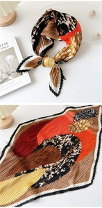 Detail of pleated silk scarf with leopard print and warm tones on a minimalist setup