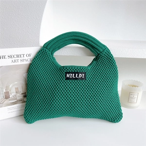 Close-up of emerald green knitted tote bag with textured knit fabric and brand label