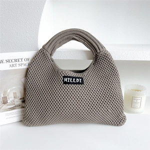 Detailed texture of knit hobo bag with Hilldi logo on a minimalist white surface