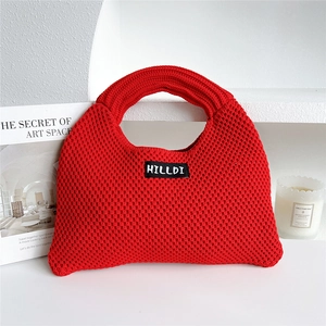 Close-up of red chunky knit dumpling tote bag with HILLDI logo label texture