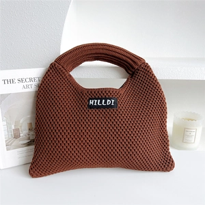 Detailed knit texture of a brown dumpling tote bag with branding on a minimalist white stage