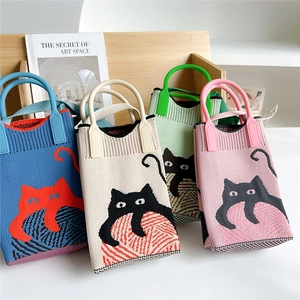 Mini knitted crossbody bags with cute cat patterns in four pastel colors on a shelf