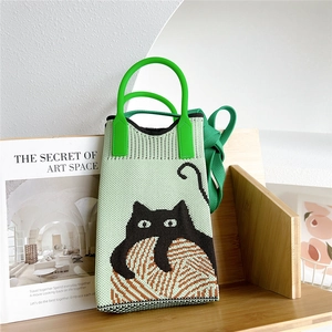 Detailed knit texture of a green shoulder bag featuring a cute black cat pattern