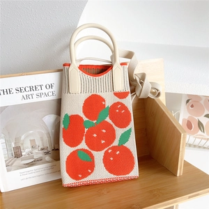 Detail of knitted cream mini bag with orange fruit patterns and rigid curved handle