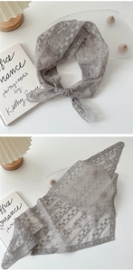 Détail d'un foulard triangle en dentelle grise montrant la texture délicate au crochet