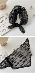 Détail d'un foulard triangle en dentelle noire avec broderie florale et bords ondulés
