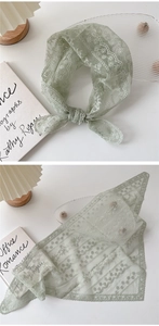 Détail d'un foulard triangle en dentelle vert clair avec broderie florale blanche