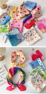 Close-up of assorted cotton-linen square scarves with floral and rainbow patterns