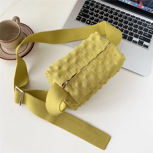 Detailed close-up of mustard yellow knitted crossbody bag with waffle texture and wide strap