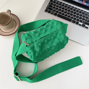 Macro detail of grass green knit crossbody bag texture with wide nylon shoulder strap
