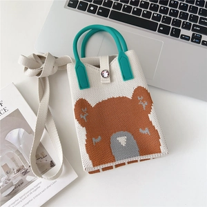 Detail of knitted beige phone bag with brown bear pattern and green resin handle