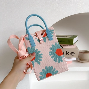 Close-up of pink knitted phone bag featuring a colorful daisy pattern and blue round handle