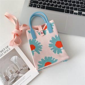 Detail of pink knitted daisy bag featuring teal handles and intricate floral patterns
