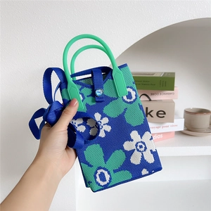 Detail of knitted floral phone bag with contrast stitching and green top handle