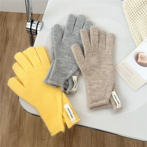 Trio of winter knitted gloves in yellow, grey, and beige with woven brand labels