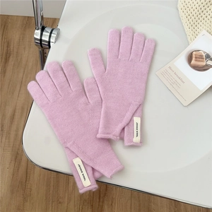 Close-up of pink knitted glove detail with woven wool label on soft cashmere fabric