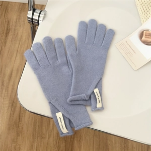 Detail of light blue knitted wool gloves showing soft texture and brand label