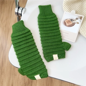 Detail der grünen Strickhandschuhe mit Rippstruktur und Stoffmarkenetikett am Handgelenk