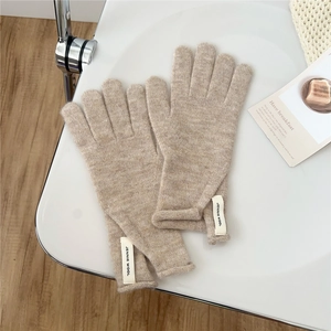 Close-up of oatmeal knitted gloves with premium wool texture and woven brand label
