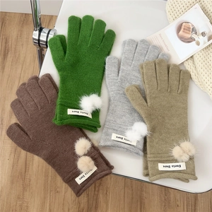 Winter knitted pom-pom gloves in brown, green, gray and khaki colors on cozy background
