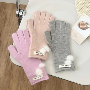Winter knitted pompom gloves in pink, beige, and grey with soft wool textures