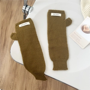 Detail of brownish-green knit fingerless gloves with a JENNIE WOOL woven label on the wrist