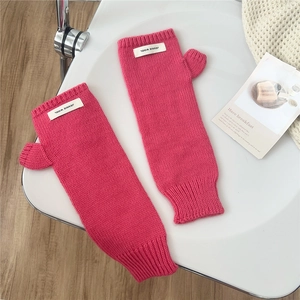 Close-up of rose pink chunky knit fingerless gloves with thumb hole and woven label