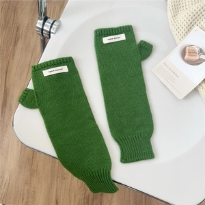 Detail of green knitted fingerless gloves with ribbed cuffs and thumb hole design