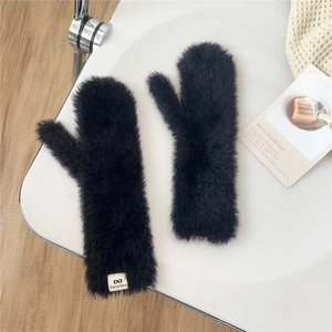 Detail of soft black plush mittens with brand label on a stylish white display tray