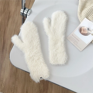 Close-up of fluffy cream plush mittens with brand label and soft faux fur texture