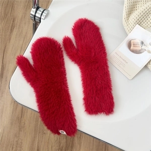 Detail of red plush mittens with soft faux fur texture and a minimalist white side label
