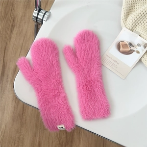 Close-up of pink plush mittens with warm thick fur texture and white brand woven label