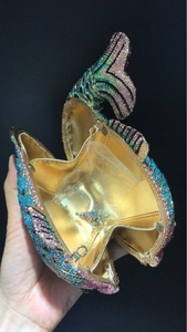 Détail macro d'une pochette de soirée en forme de poisson avec strass colorés et intérieur doré