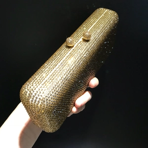 Close-up of golden rectangular evening clutch bag covered in shimmering rhinestones