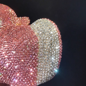 Gros plan détaillé d'une pochette cœur avec strass roses et blancs sur fond noir élégant