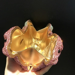 Détail d'une pochette de soirée en forme de fleur avec strass roses et intérieur doré