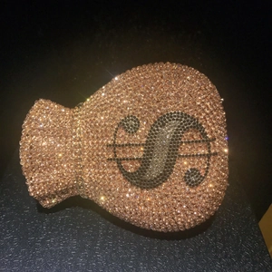 Macro view of crystal encrusted money bag clutch featuring dollar sign and chain