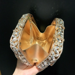 Macro detail of heart-shaped clutch showing sparkling crystals and gold chain strap
