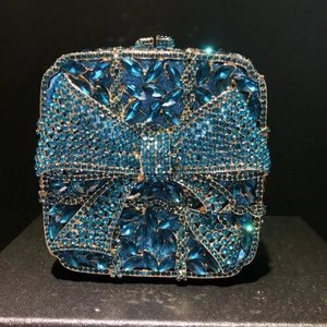 Close-up of sparkling peacock blue rhinestone bow on a luxury evening clutch bag