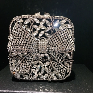 Detailed view of silver diamond clutch bag with sparkling rhinestone bow on black background