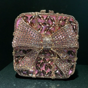 Close-up of sparkling diamond clutch bag featuring a pink crystal bow design