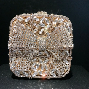 Detailed close-up of luxurious golden bow clutch with sparkling crystals and metal frame
