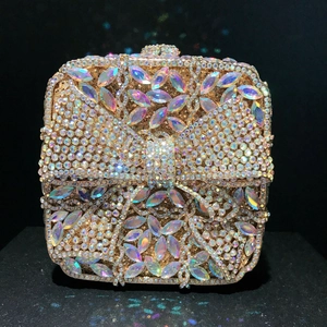 Macro detail of golden evening clutch with diamond bow and colorful crystal leaf patterns