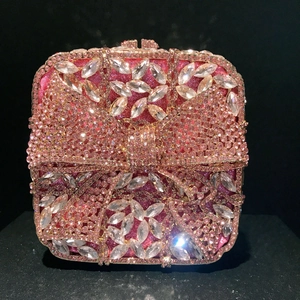 Detail of pink crystal clutch bag featuring a sparkling bow and rhinestone buckle