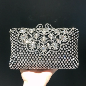 Détail de pochette de soirée argentée avec motifs de fleurs en cristal et fermoir métal