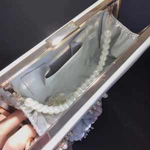 Detail view of the white floral evening clutch with pearls and grey fabric lining inside